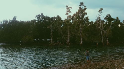 Rear view of shirtless boy standing in water