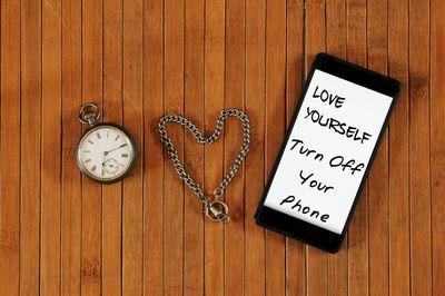 Smart phone and pocket watch on wooden table