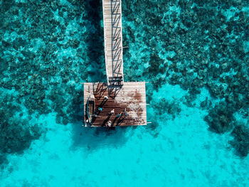 Top down aerial view over the end of wooden jetty with unidentified kids on it.