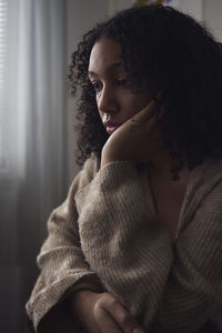 Pensive young woman sitting at home