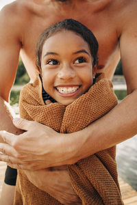 Father embracing daughter wrapped in towel
