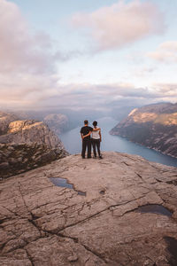 Couple standing at cliff at preikestolen, norway during sunset