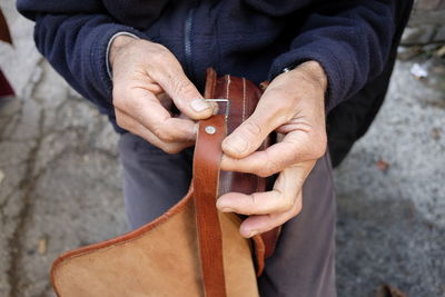 Midsection of man holding leather bag