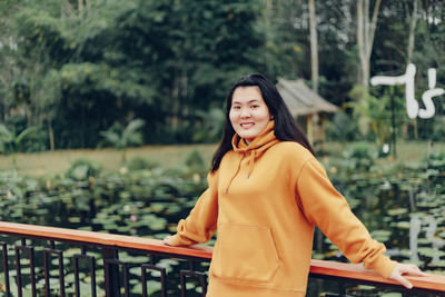 Portrait of young woman standing against trees