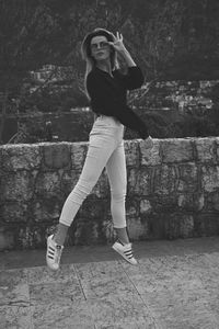 Portrait of young woman standing against wall