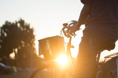 Man riding bicycle against sky during sunset