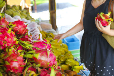 Midsection of woman with vegetables for sale at market stall