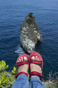 Low section of woman on rock by sea