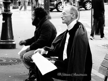 Young man sitting on sidewalk