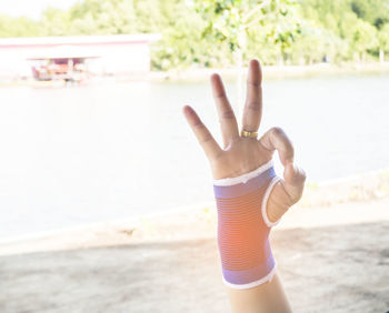 Close-up of hand showing peace sign on beach
