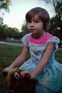 Portrait of girl sitting on spring ride in park at dusk