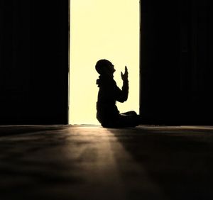 Side view silhouette of man praying in mosque