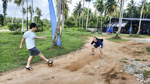 Father and son having fun playing soccer with a coconut in the playground.