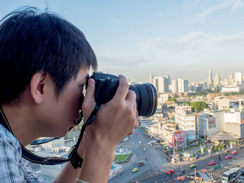 Portrait of man photographing with cityscape