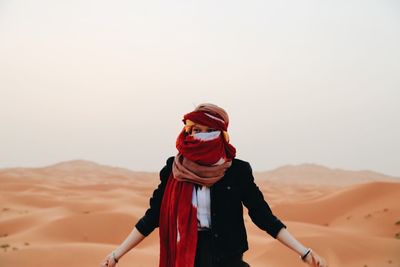 Young woman with headscarf standing on sand dune