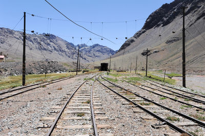 Railroad track by mountains against clear sky