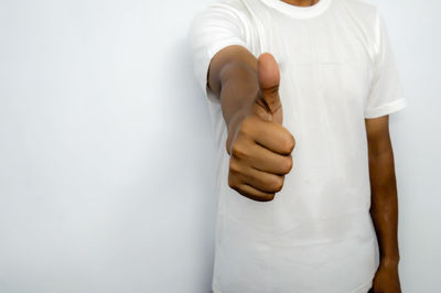 Midsection of man standing against white wall