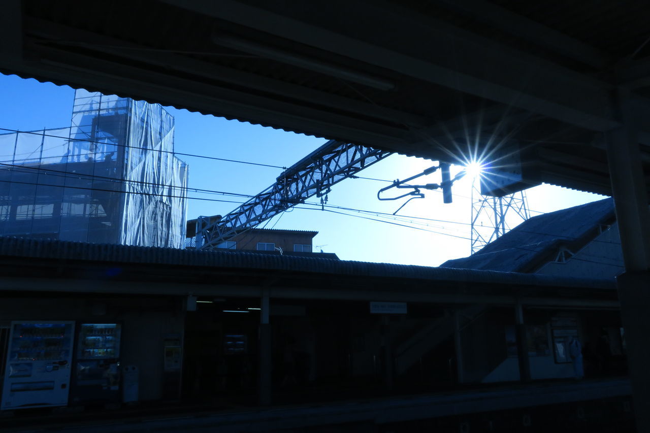 LOW ANGLE VIEW OF RAILROAD STATION AGAINST BRIGHT SKY