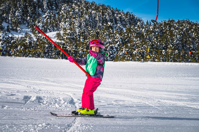Young skier, a child, having fun when riding up on a ski drag lift, andorra