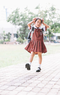 Full length of schoolgirl playing at paving stones