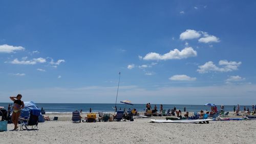 People relaxing on beach against blue sky