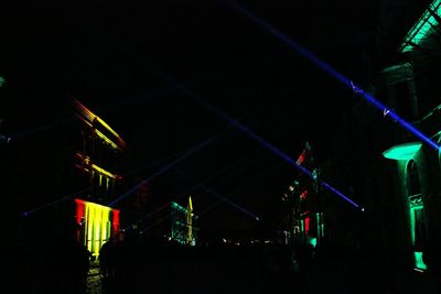 Low angle view of illuminated city against sky at night