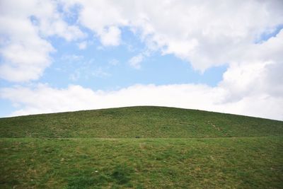 Scenic view of grassy field against cloudy sky