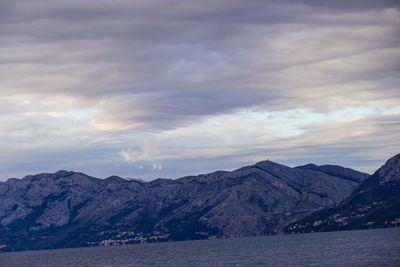 Scenic view of sea by mountains against sky