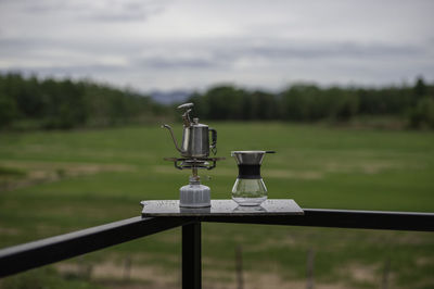 Close-up of metal structure on field against sky