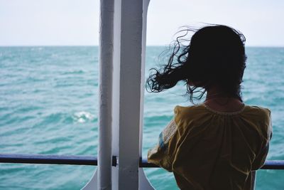 Rear view of woman with tousled hair looking at sea