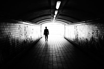 Silhouette man walking in illuminated tunnel