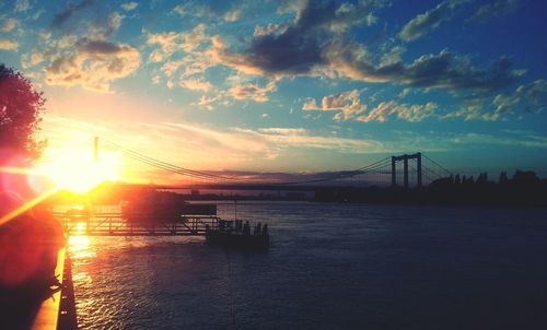 Suspension bridge over river during sunset