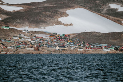 Sea by houses on snow covered mountain