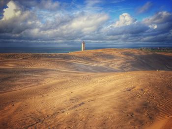 Scenic view of beach against cloudy sky