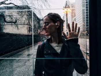 Young woman seen through wet glass window during monsoon