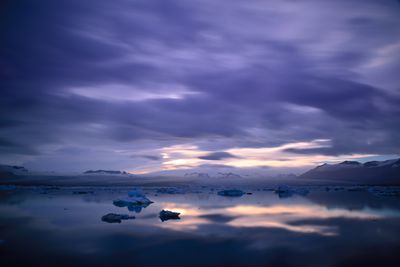 Scenic view of lake against cloudy sky during dusk