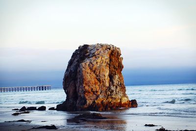 Rock formation on beach against sky