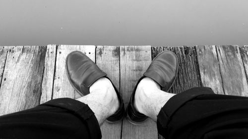 Low section of man standing on wood