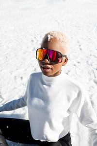 A young african american woman wearing sunglasses having fun in the snow on a winter day