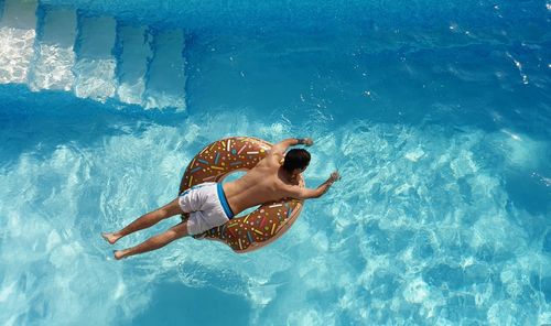 High angle view of man on donut inflatable ring in swimming pool