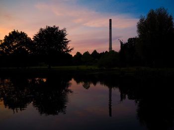 Silhouette trees by lake against sky during sunset