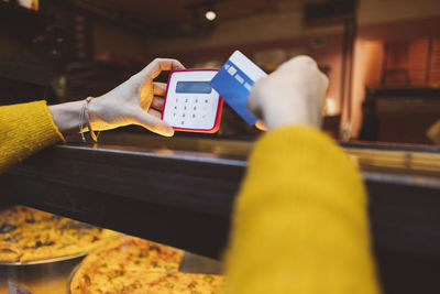 Hands of woman making payment through credit card at cafe