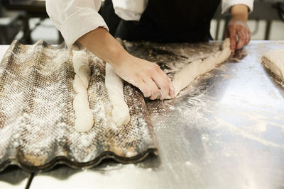 Midsection of female chef shaping raw loaf of bread in commercial kitchen