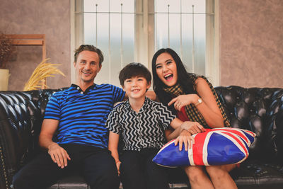 Portrait of happy family sitting on sofa at home