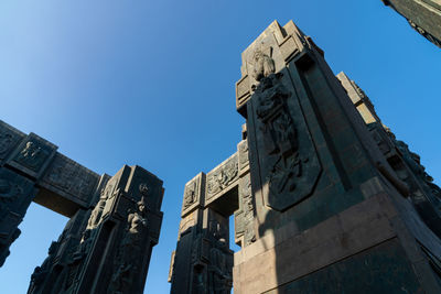 Low angle view of statue amidst buildings against sky