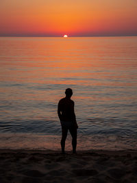 Silhouette man standing on beach during sunset