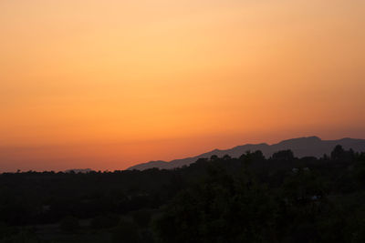 Scenic view of silhouette mountains against orange sky