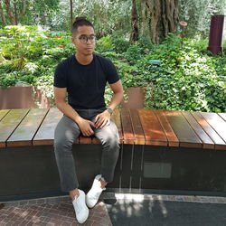 Portrait of young man sitting against plants