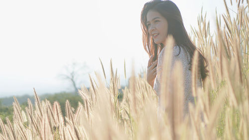 Portrait of smiling young woman on field against sky