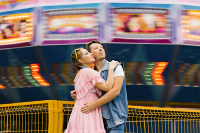 Happy couple in love enjoying each other in an amusement park and cuddling